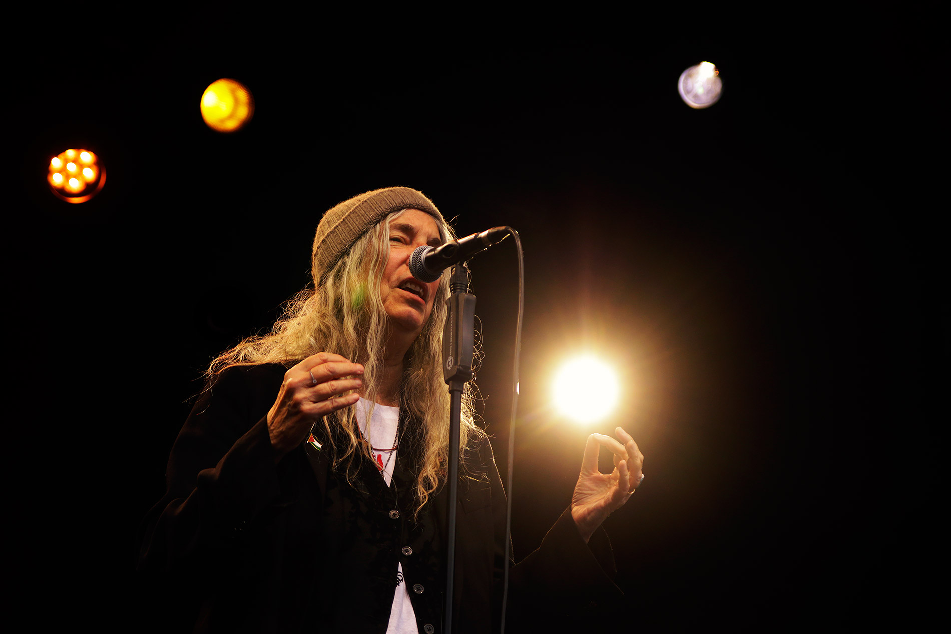 Patti Smith’s voice and gesture meet in one bright moment as she sings with a spark in her hand at the Allas Live outdoor venue in Helsinki on July 25, 2026. Photograph: TONY ÖHBERG/FINLAND TODAY