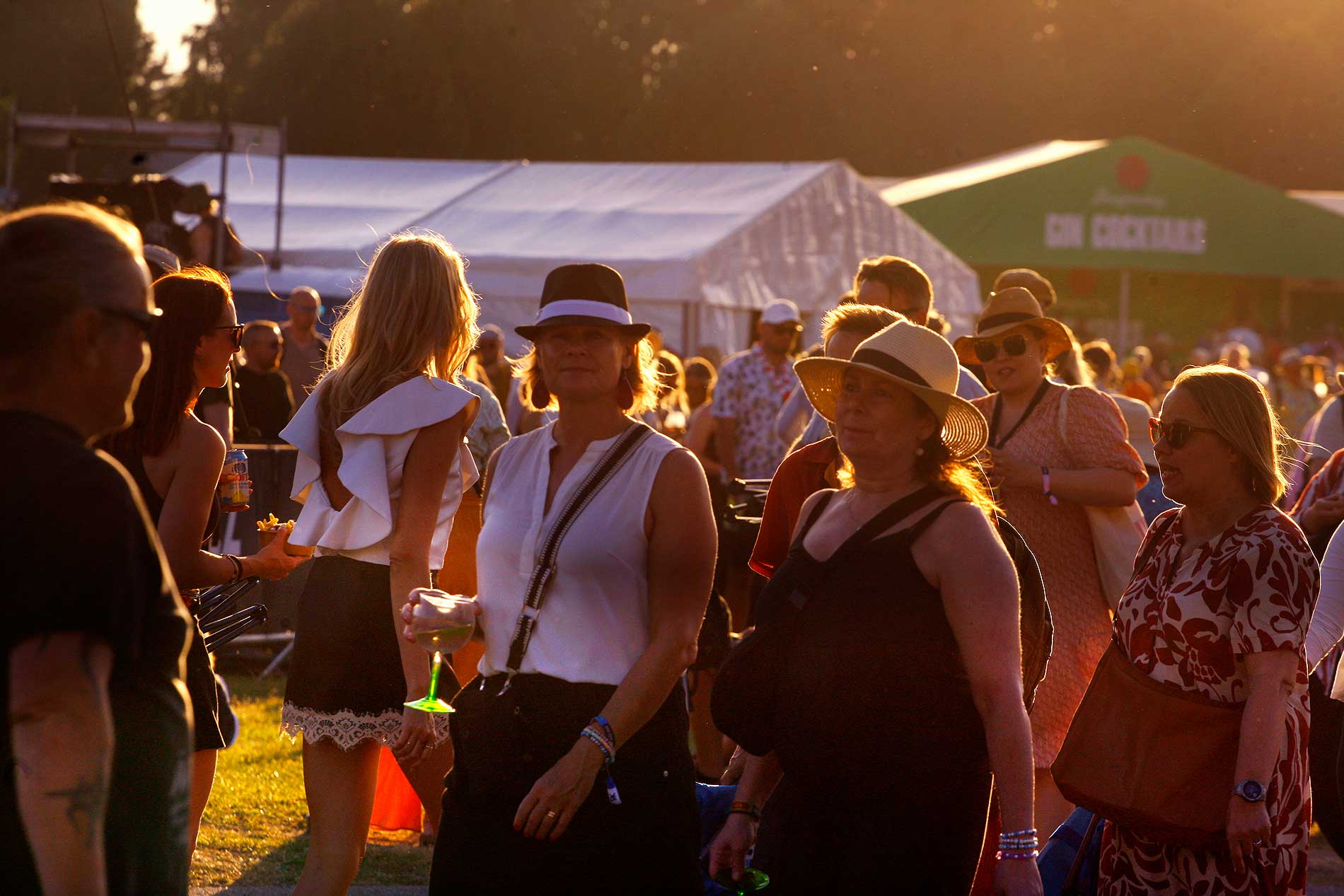 Two women walk on through the sunlit festival haze, wine glasses catching the light as Sugababes plays nearby. Photograph: TONY ÖHBERG/FINLAND TODAY