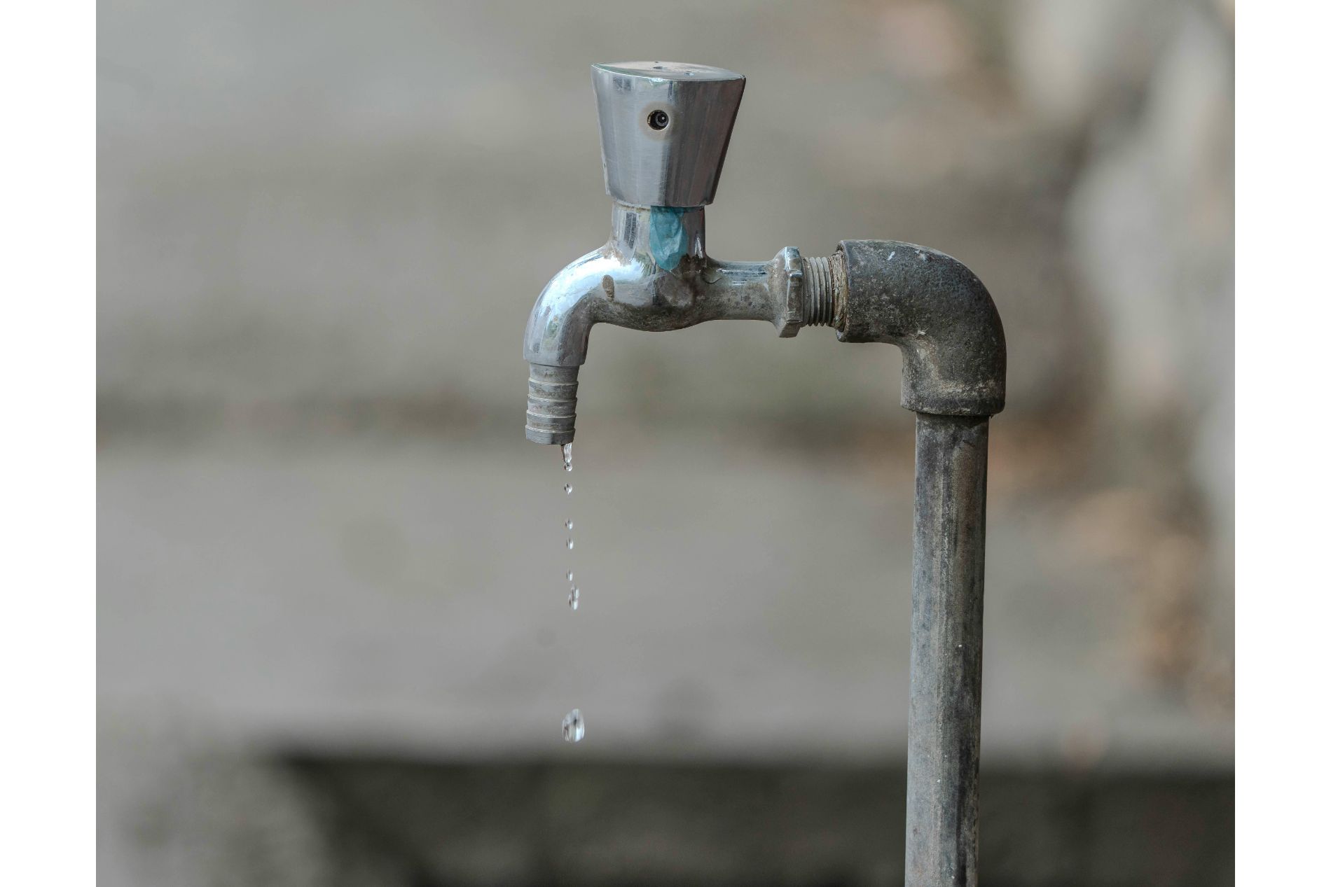 A picture of dripping water from a tap that seems old. Photograph by Pexels.