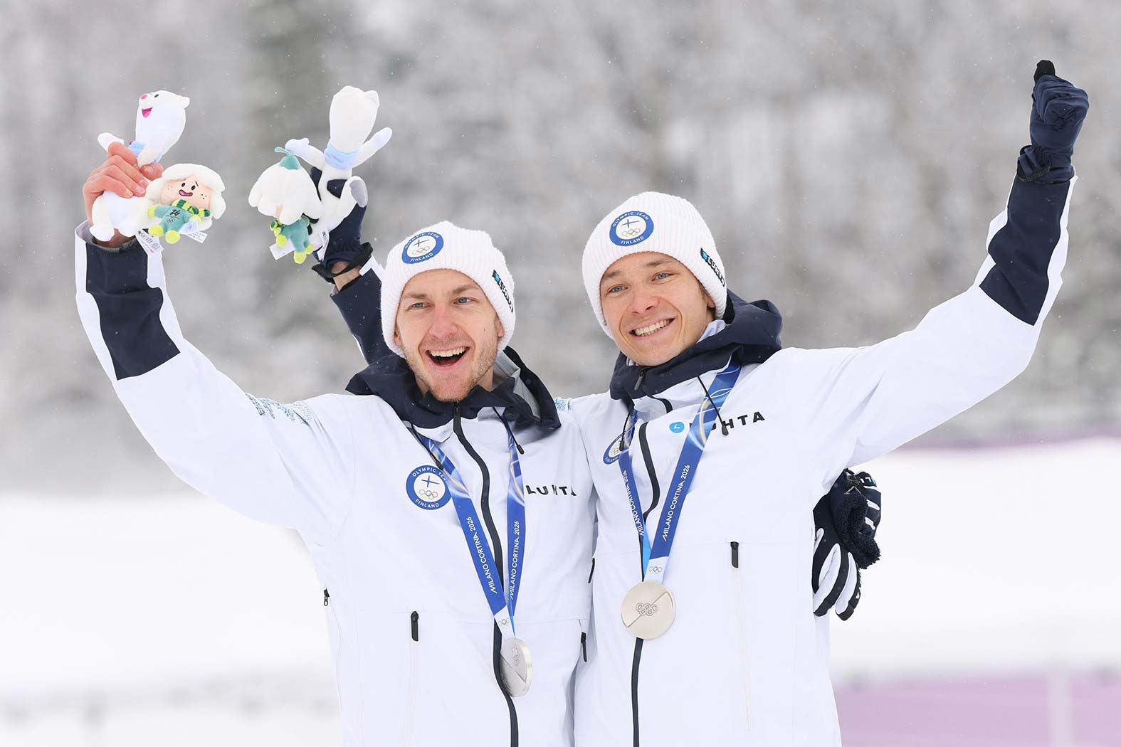 Ilkka Herola (left) and Eero Hirvonen celebrate after winning silver medals in the Nordic combined team event at the Milan-Cortina 2026 Winter Olympics, standing together with their medals in a photograph by Yohei Osada/AFLO/EASTPRESS.
