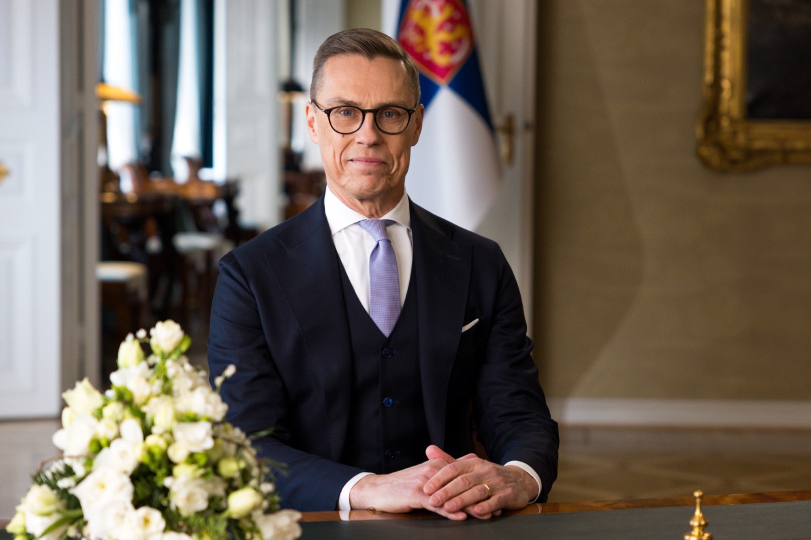 President Alexander Stubb stands at a podium delivering his New Year's speech on January 1, 2026, with the Finnish flag visible in the background. Photo by Emmi Syrjäniemi, Office of the President of the Republic.