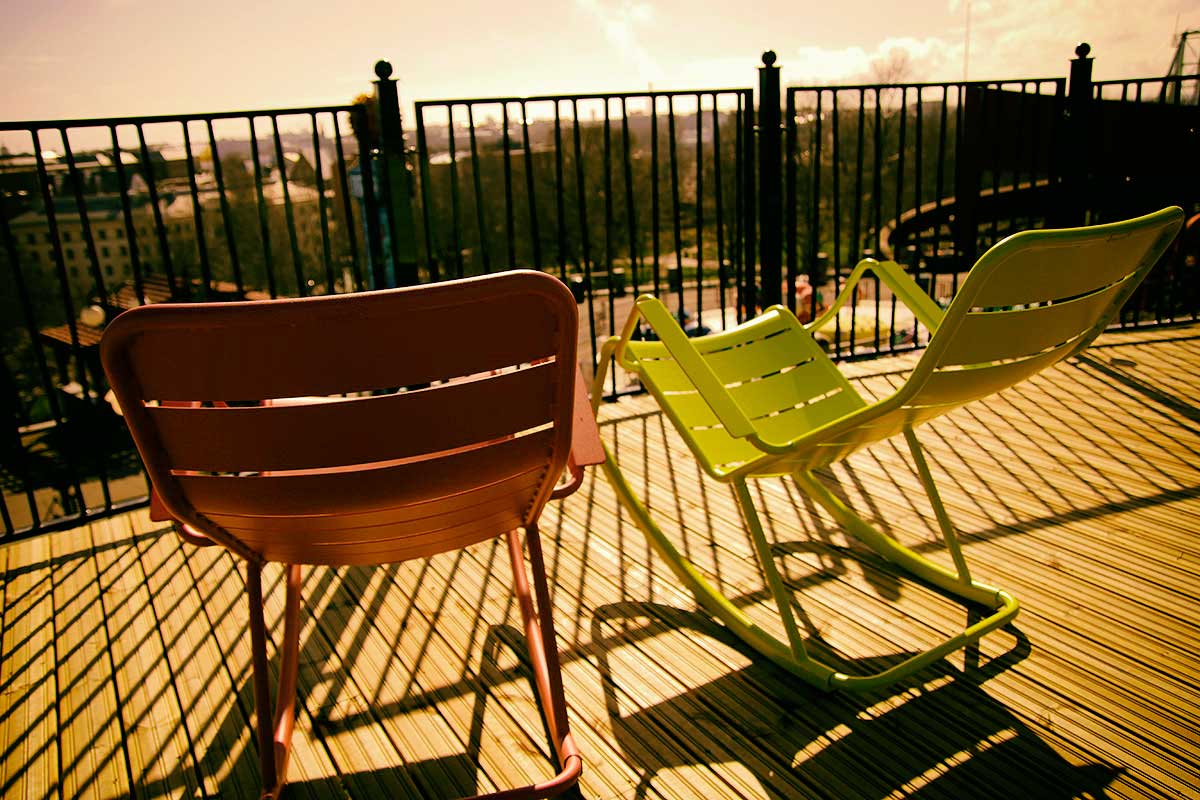 Photograph by Tony Öhberg showing two chairs on an open-air patio located high on a rooftop under sunny weather conditions.